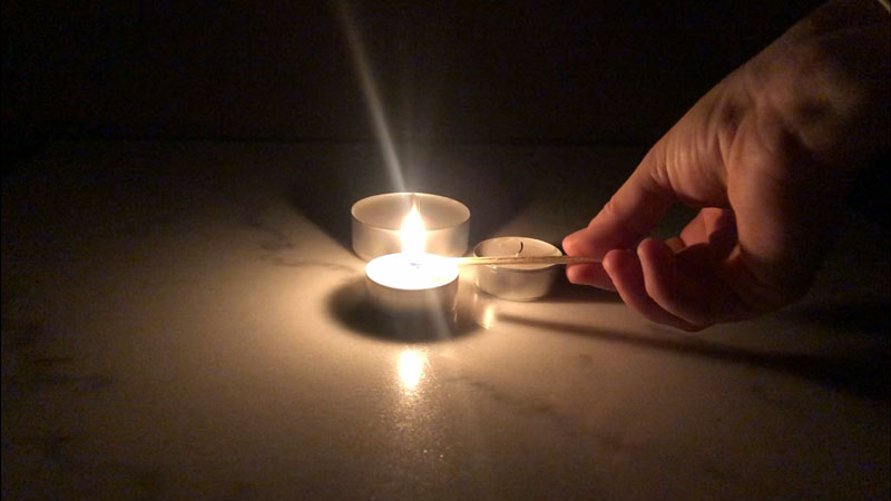 Tre värmeljus som tänds i ett mörkt rum
