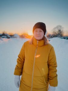 Jonna iklädd gul vinterjacka i ett snötäckt landskap.