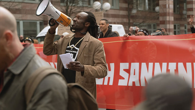 Man som ropar i megafon ett demonstrationsled