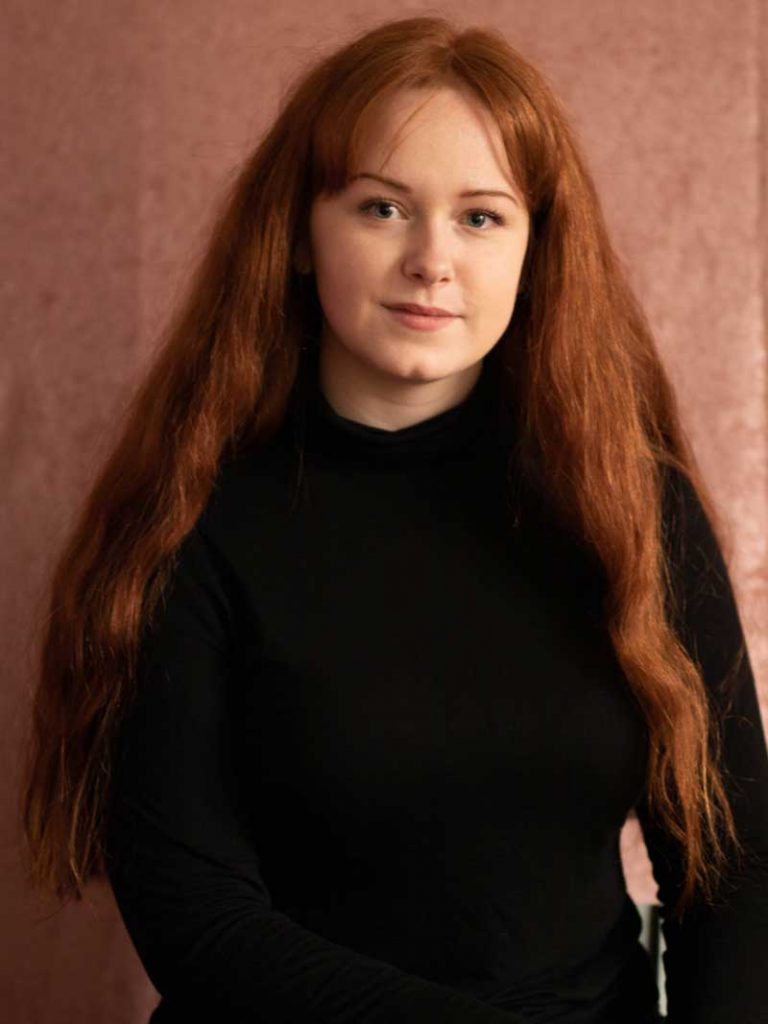 Reporter Alice framför en rosa bakgrund.