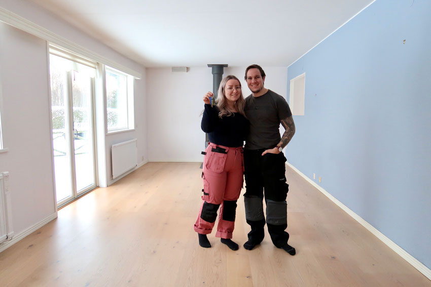 En tjej med rosa arbetsbyxor och en kille med svarta arbetsbyxor. En blå vägg och ett tomt rum.