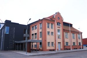 En röd byggnad intill en svart byggnad, med massa fönster.