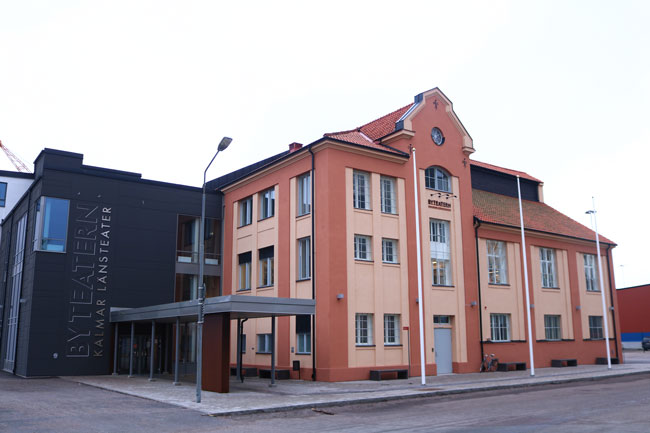 En röd byggnad intill en svart byggnad, med massa fönster.