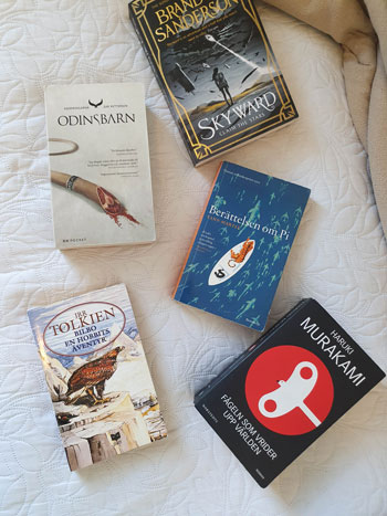 Fem böcker på en säng.